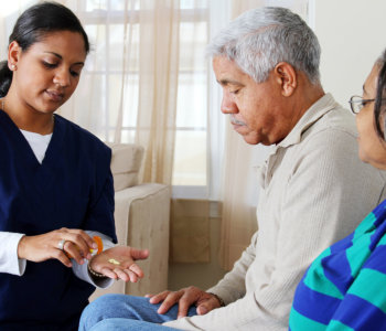 caregiver giving medicine to an elder man