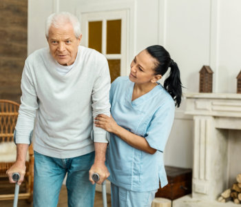 caregiver assisting an elder man to walk